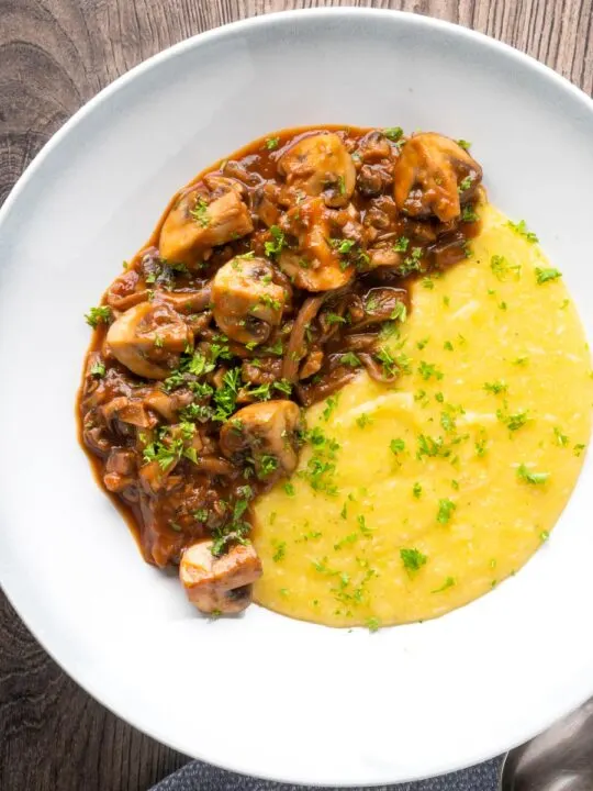 Overhead vegan mushroom ragu served with polenta and a parsley garnish