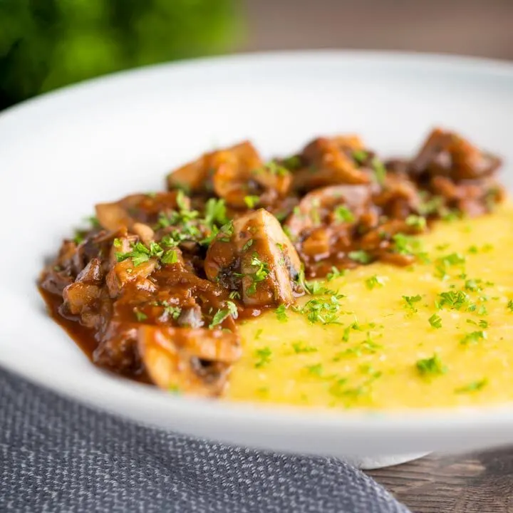 Super chunky vegan mushroom ragu served with polenta and a parsley garnish.