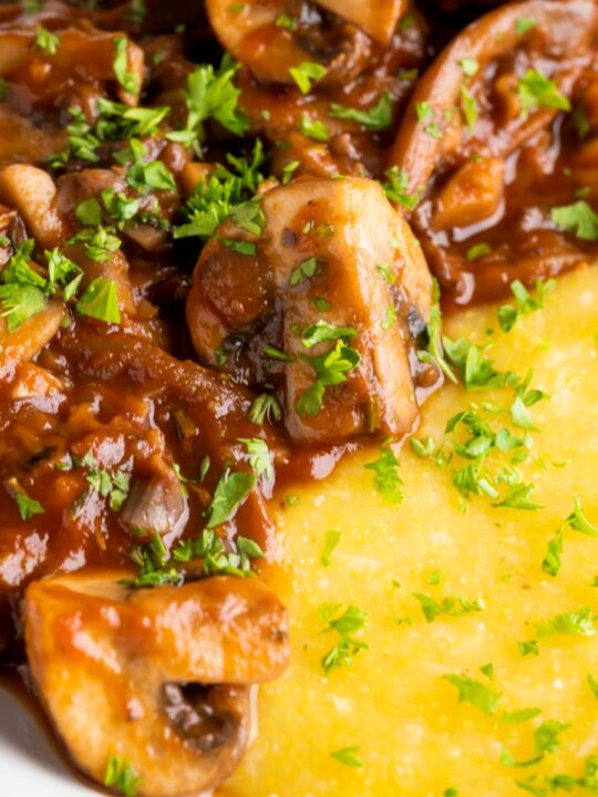 Close up vegan mushroom ragu served with polenta and a parsley garnish