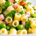 Pasta e piselli or pasta with peas and ham garnished with chopped parsley featuring a title overlay.