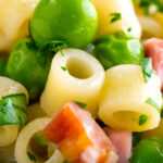 Close up pasta e piselli or pasta with peas and ham featuring a title overlay.