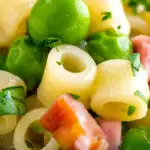 Close up pasta e piselli or pasta with peas and ham featuring a title overlay.