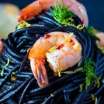 Close up prawn pasta with squid ink spaghetti fennel and chilli.