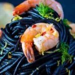 Close up prawn pasta with squid ink spaghetti fennel and chilli.