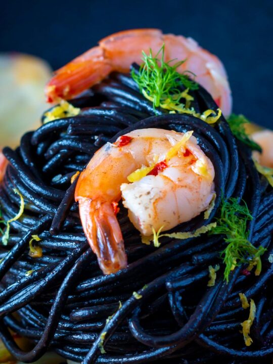 Close up prawn pasta with squid ink spaghetti fennel and chilli.