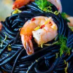 Close up prawn pasta with squid ink spaghetti fennel and chilli featuring a title overlay.