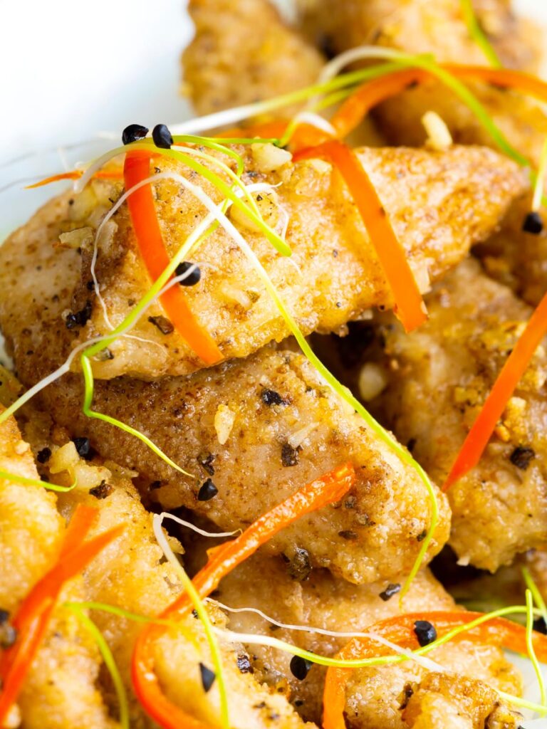Close up crispy Chinese salt and pepper chicken with shredded chilli and sprouted onion seeds.