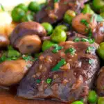 Close up chicken liver stew with button mushrooms and peas in red wine sauce featuring a title overlay.