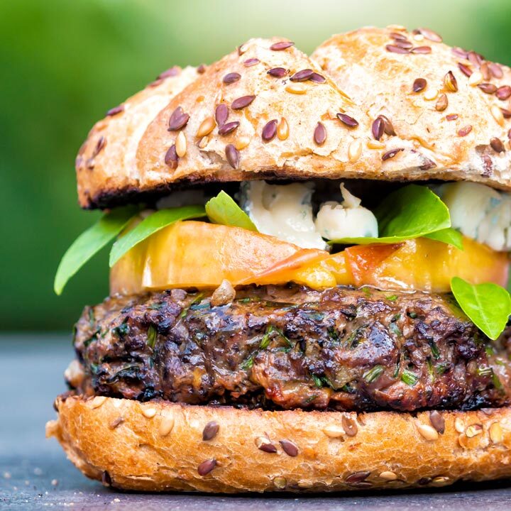 Venison burger served on a bun topped with blue cheese, peaches & basil.