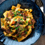 Overhead rich venison ragu sauce served with pappardelle pasta in a blue bowl featuring a title overlay.