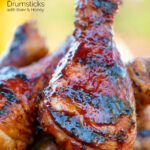 Close up bbq chicken drumsticks with a beer, paprika and honey glaze featuring a title overlay.