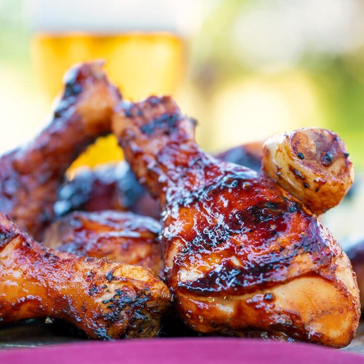 Grilled BBQ chicken drumsticks with a beer, paprika and honey glaze with a beer in the background.