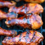 BBQ chicken drumsticks with a beer, paprika and honey glaze cooking on the grill.