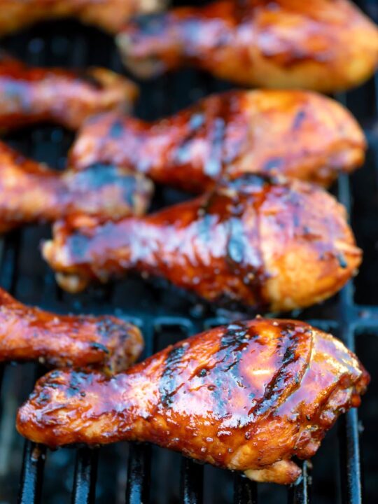BBQ chicken drumsticks with a beer, paprika and honey glaze cooking on the grill.