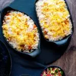 Overhead chicken tikka biryani served in stoneware bowls with kachumber salad and raita.