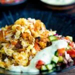 Chicken tikka biryani served in a bowl with kachumber salad and mint raita.