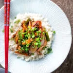Overhead Chinese chicken with black bean sauce serve in a white bowl with rice.