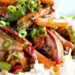 Close up Chinese chicken with black bean sauce serve in a white bowl with rice.