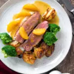 Over head pan fried duck breast with orange sauce served with roast potatoes.