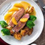 Over head pan fried duck breast with orange sauce served with roast potatoes featuring a title overlay.