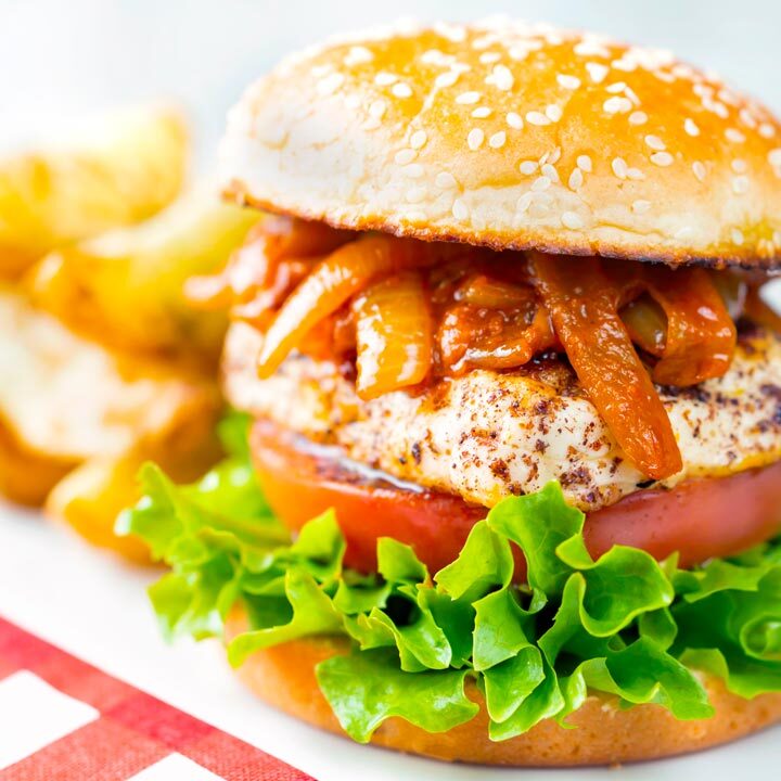 Halloumi burger with harissa onions, tomato & lettuce on a sesame seed bun with potato wedges.