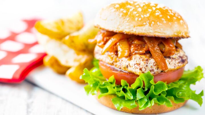 Halloumi burgers with harissa onions, tomato & lettuce on a sesame seed bun.