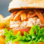 Halloumi burgers with harissa onions, tomato & lettuce on a sesame seed bun.
