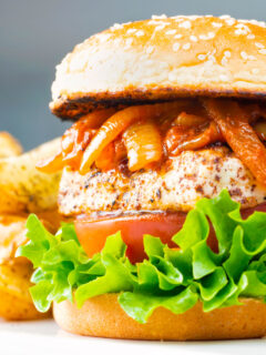 Halloumi burgers with harissa onions, tomato & lettuce on a sesame seed bun.