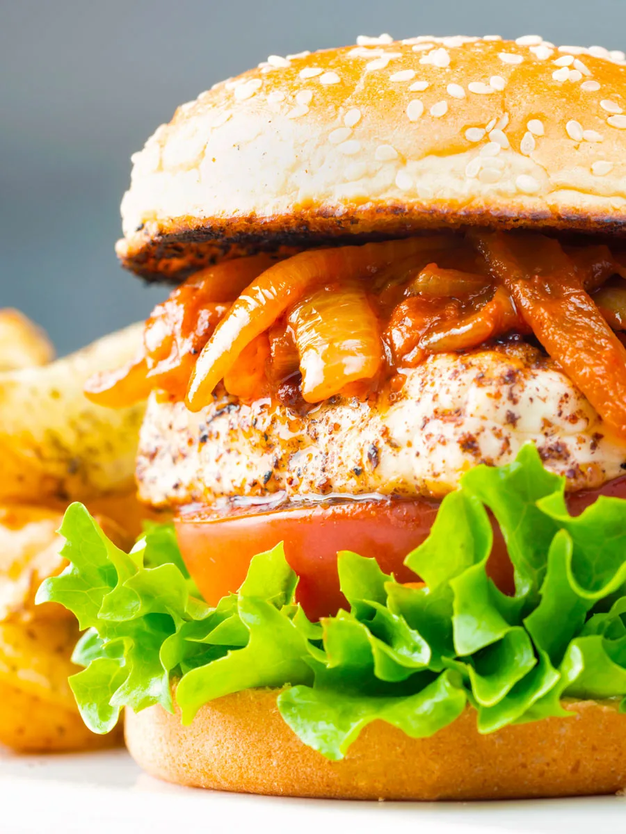 Halloumi burgers with harissa onions, tomato & lettuce on a sesame seed bun.