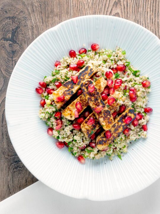 Overhead seared halloumi cheese salad with pomegranate and couscous.