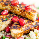 Close up halloumi cheese salad with pomegranate and couscous featuring a title overlay.