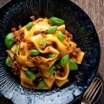 Over head Lamb ragu with pappardelle pasta and fresh basil.