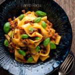 Over head Lamb ragu with pappardelle pasta and fresh basil featuring a title overlay.