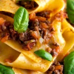 Close up lamb ragu with pappardelle pasta and fresh basil.