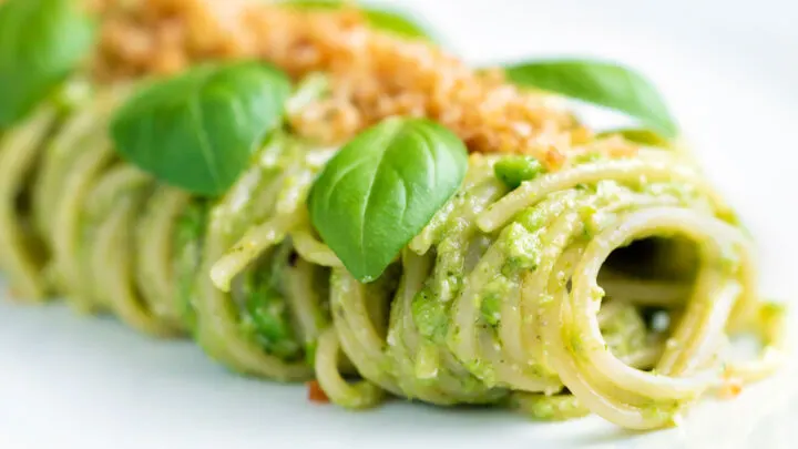 Pea pesto pasta served with spaghetti and fresh basil leaves.