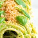 Peas pesto served as a sauce for pasta with a breadcrumb crust featuring a title overlay.