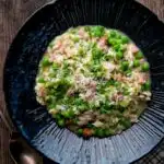Overhead pea and ham risotto served in a blue bowl.