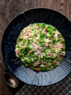 Overhead pea and ham risotto served in a blue bowl.