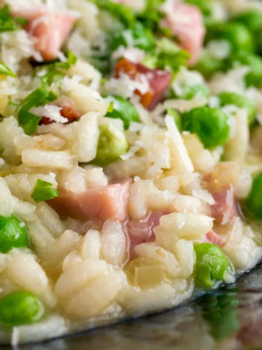 Close up pea and ham risotto served in a blue bowl.