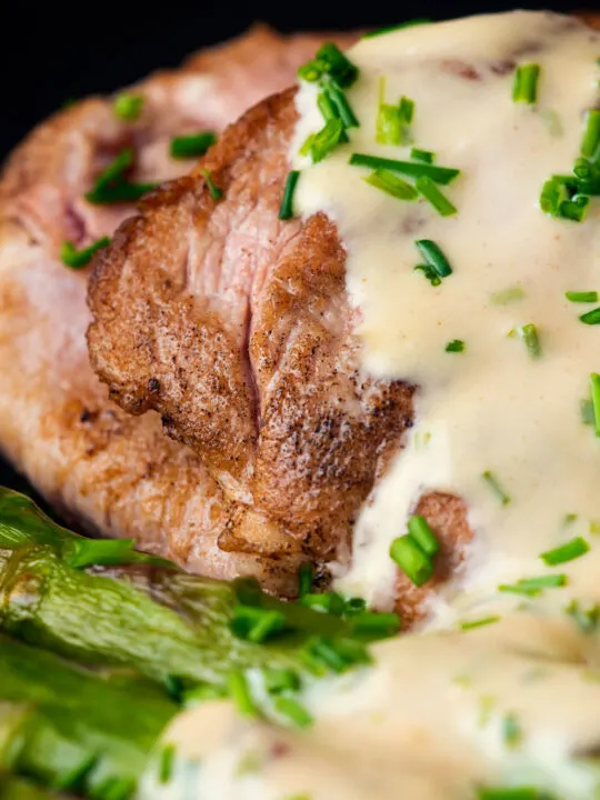 Close up pork fillet medallions with camembert cheese sauce, potatoes & asparagus.