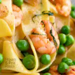 Close up prawn and peas pasta with pappardelle and shredded basil featuring a title overlay.