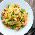 Overhead prawn and pea pasta with pappardelle served in a textured bowl.