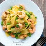 Overhead prawn and pea pasta with pappardelle served in a textured bowl featuring a title overlay.