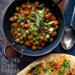 Overhead vegan Punjabi chole masala curry served in an iron karai featuring a title overlay.