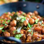 Vegan Punjabi chole masala curry or chana masala served in an iron karai featuring a title overlay.