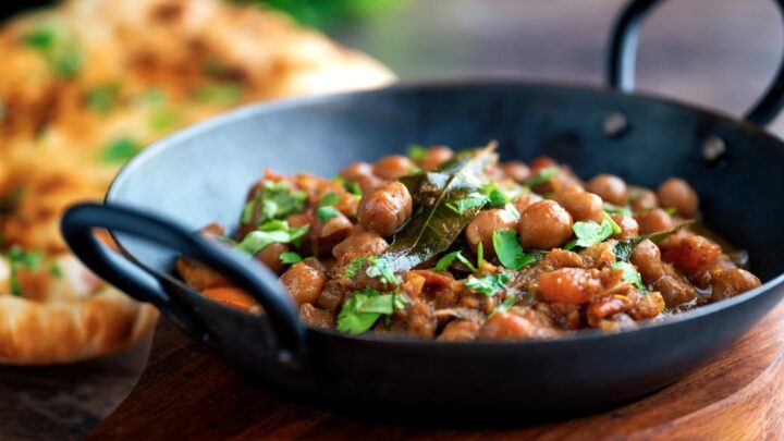 Punjabi chole masala curry or chana masala served in an iron karai with naan bread.