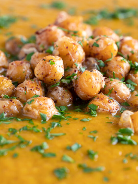 Close up spicy roasted carrot soup with crispy chickpea croutons.