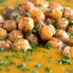 Close up spicy roasted carrot soup with crispy chickpea croutons featuring a title overlay.