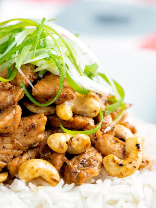 Close up Szechuan chicken with cashew nuts and spring onion served on white rice.