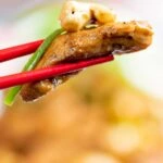 Close up Szechuan chicken with being held with chopsticks.